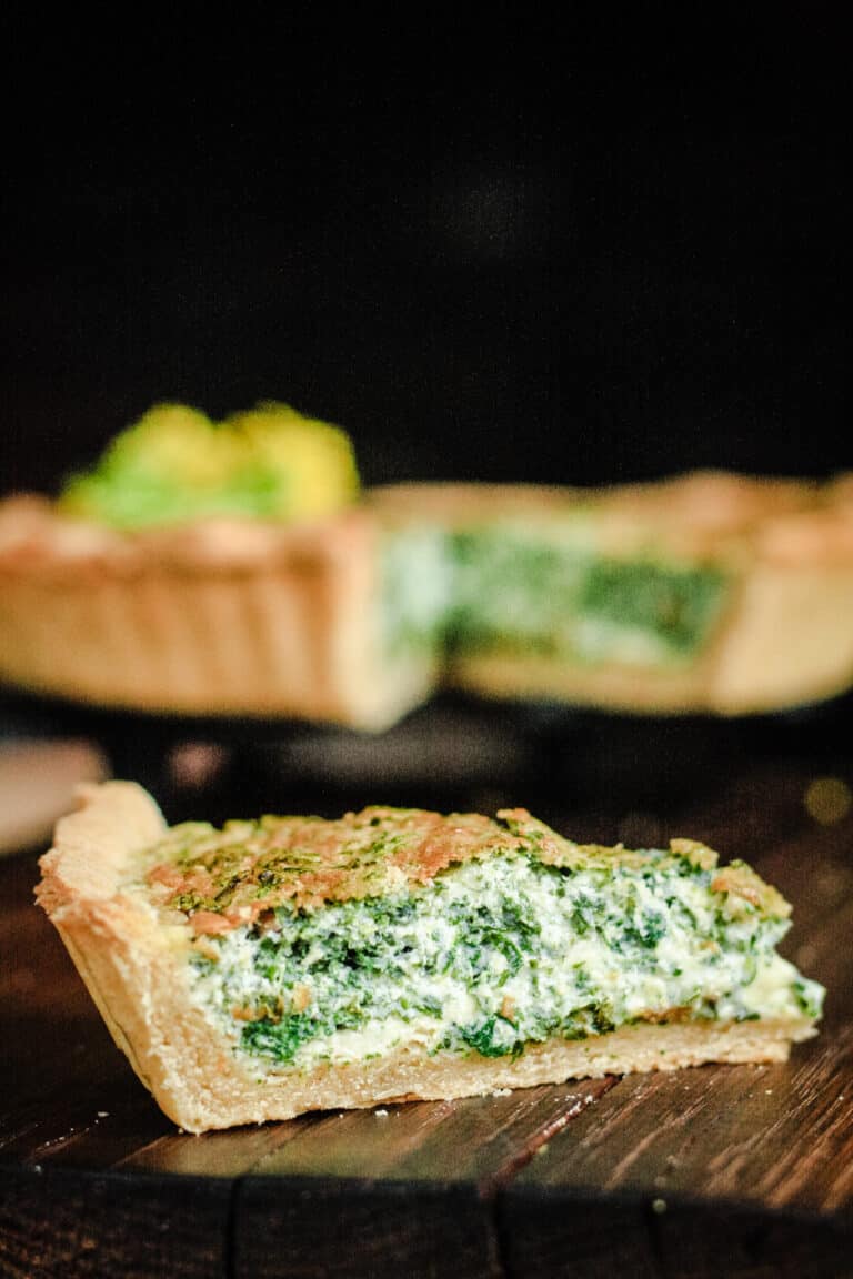 A piece of quiche sitting on top of a wooden cutting board