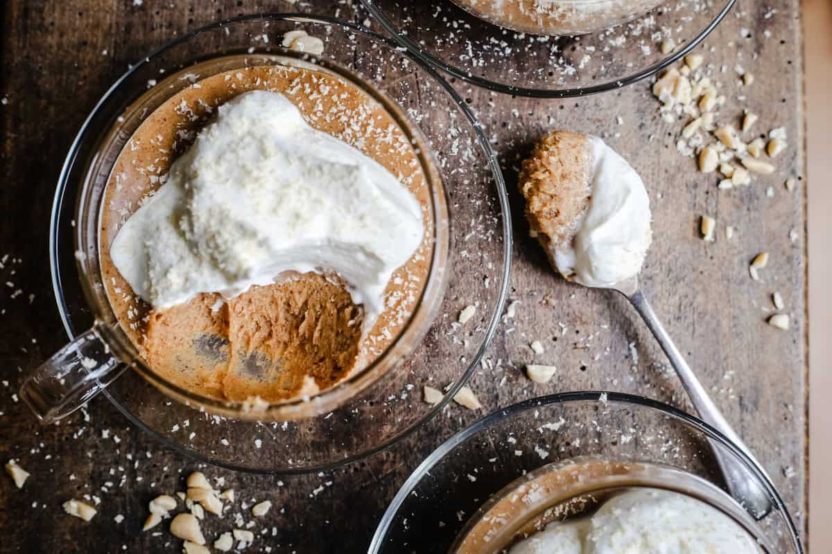 A cup of chocolate mousse and cream on a table with spoon
