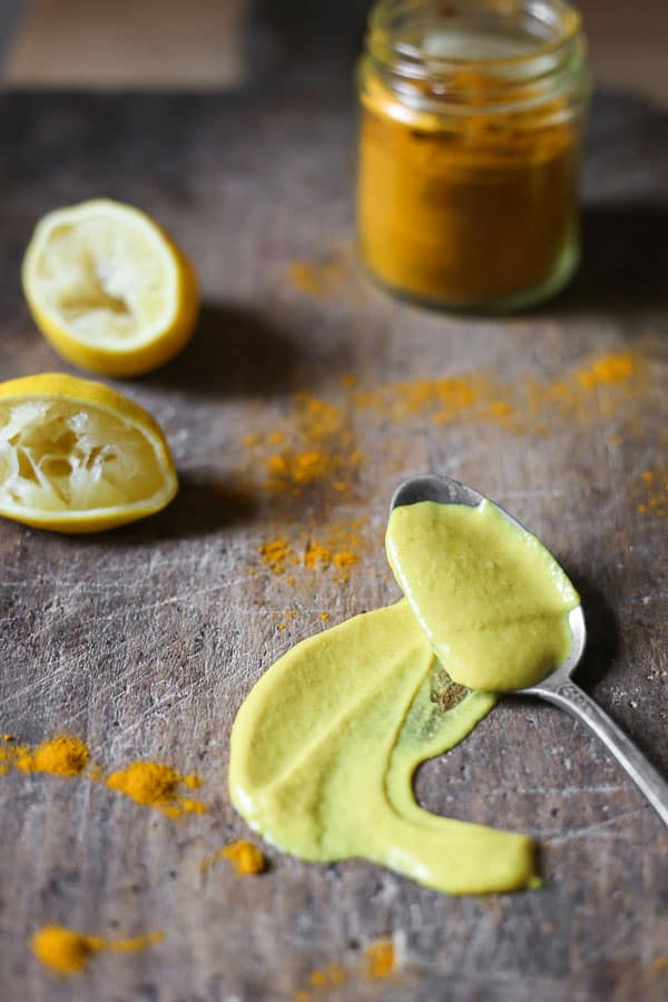 tahini dressing in a spoon smeared onto wooden board