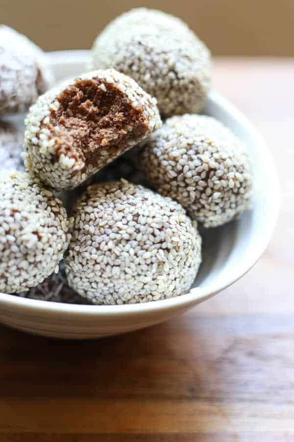 Chocolate Tahini Energy Balls in a bowl, one with a bite taken out
