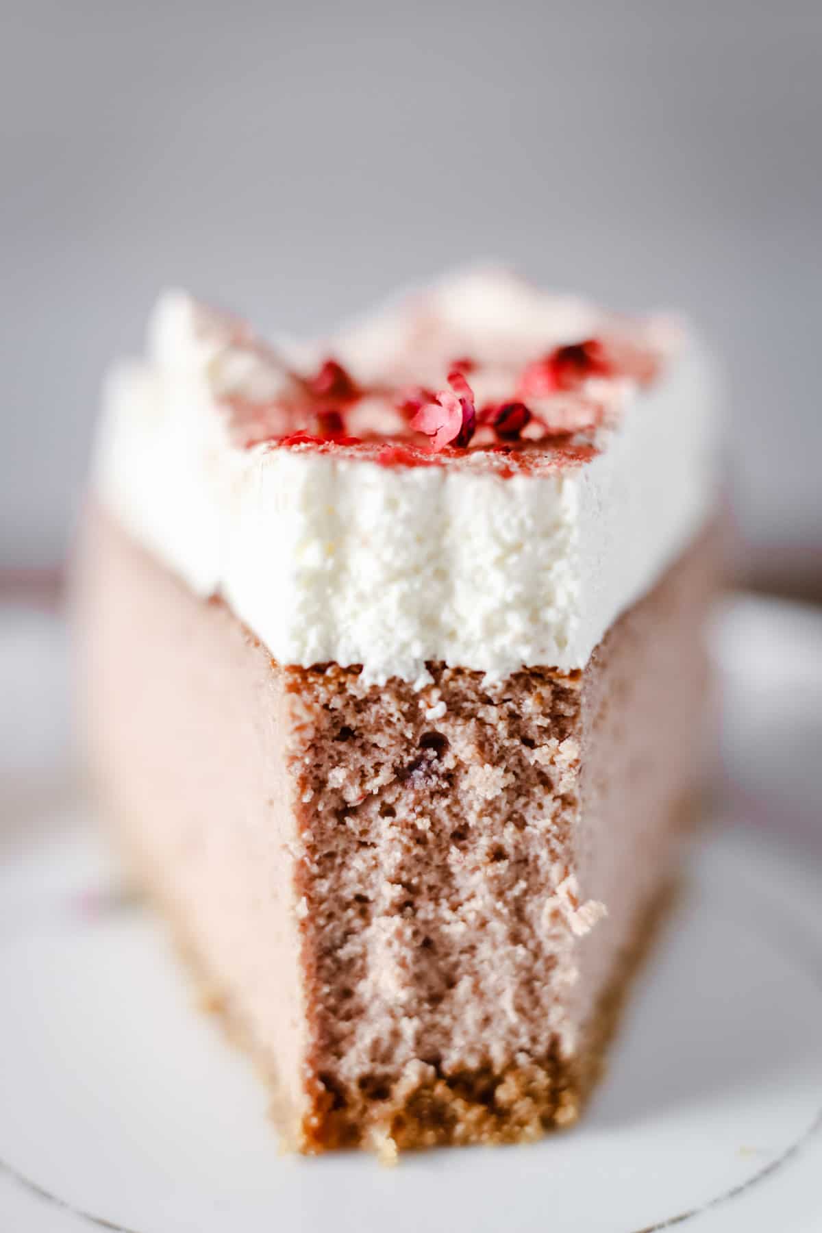Close up of a slice of Strawberry Pink Peppercorn Cheesecake with a bite taken out