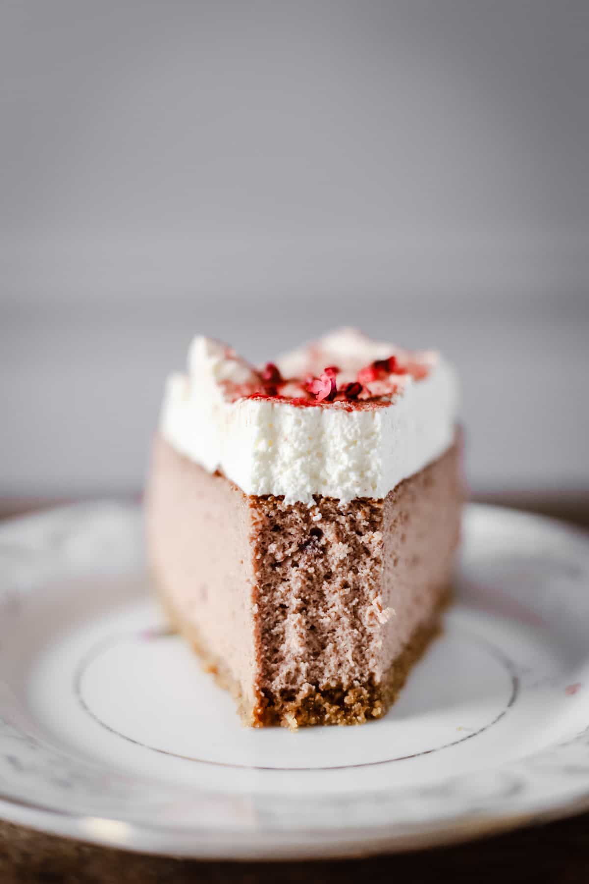 Close up of a slice of Strawberry Pink Peppercorn Cheesecake with a bite taken out