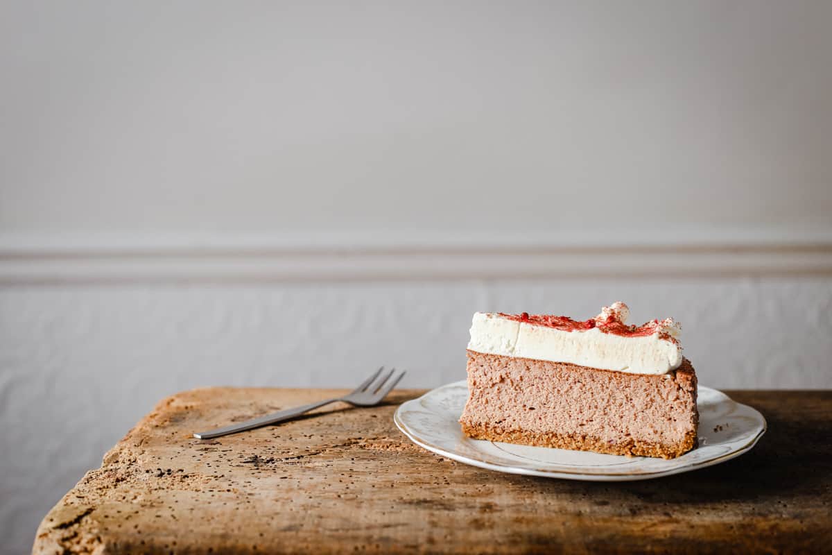 A slice of Strawberry Pink Peppercorn Cheesecake on a plate