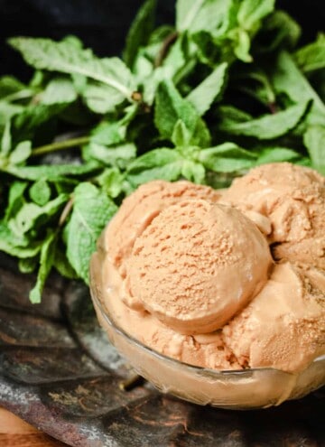 A bowl of Butter Mint Ice Cream in front of some mint leaves