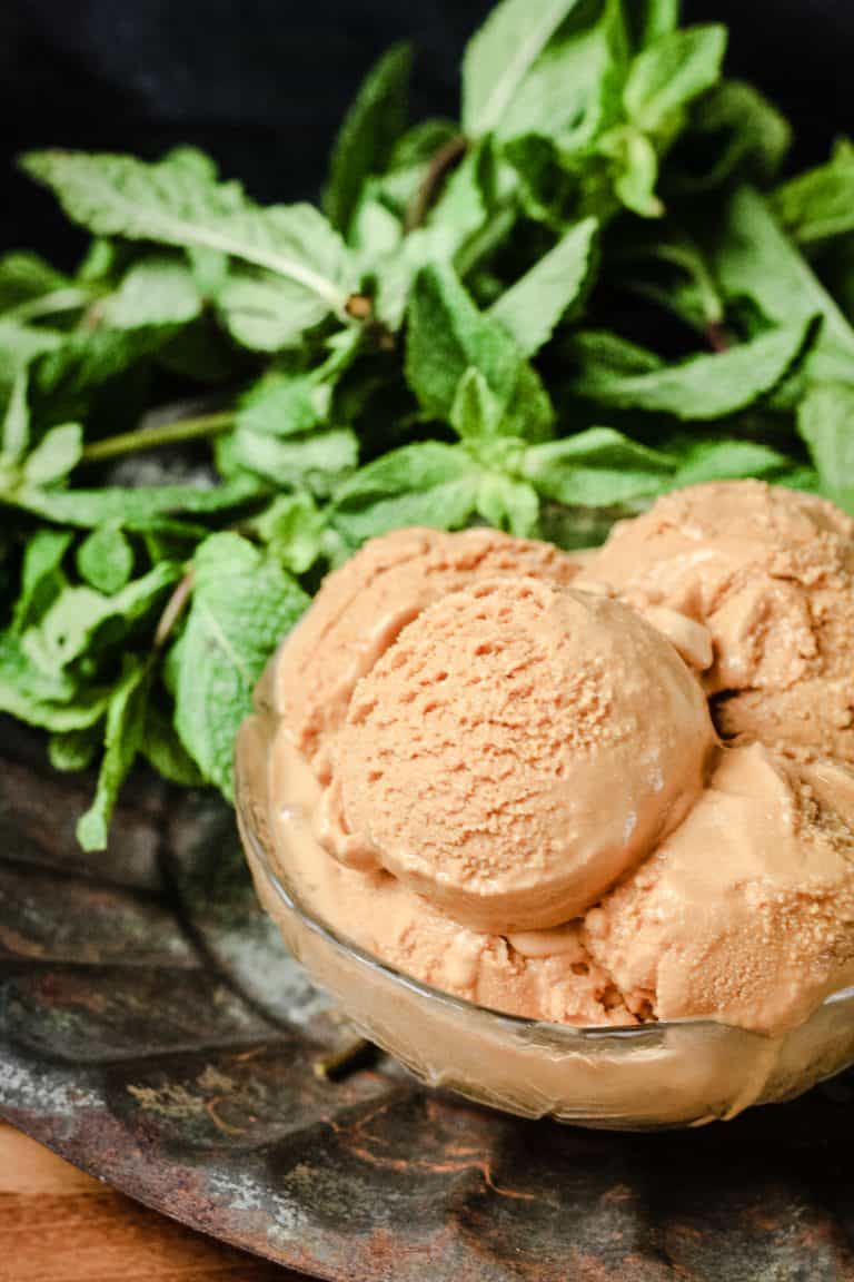 A bowl of Butter Mint Ice Cream in front of some mint leaves