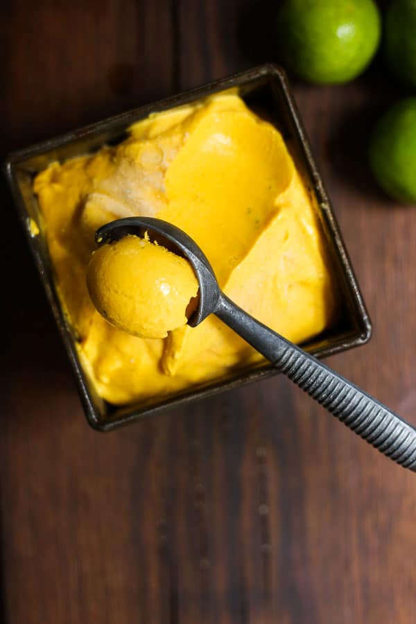 spoon scooping out mango fro yo from a bowl