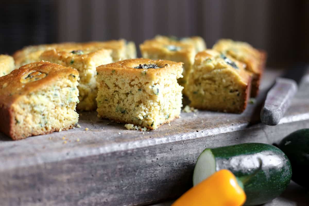 Jalapeno Honey Courgette Cornbread on a wooden board with a knife next to courgette and jalapenos