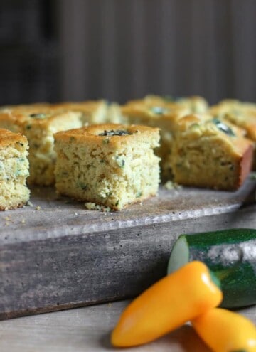 Jalapeno Honey Courgette Cornbread on a wooden board with a knife next to courgette and jalapenos