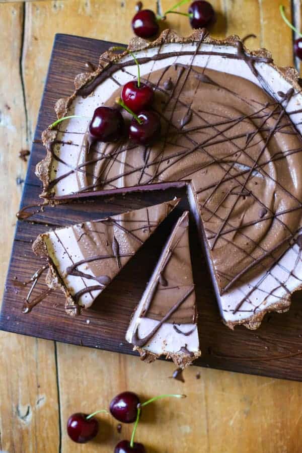 No-Bake Frozen Cherry Chocolate Pie with slices cut on a wooden board on a wooden table with cherries