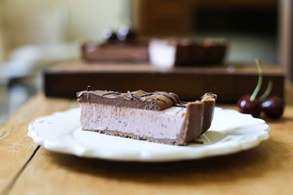 A slice of No-Bake Frozen Cherry Chocolate Pie on a plate on a wooden table