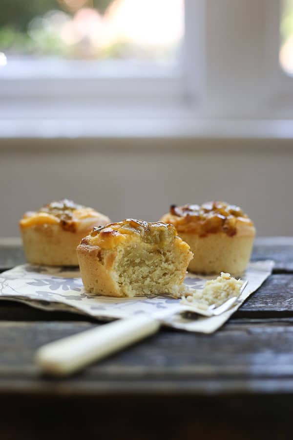 gooseberry friands with a bite taken out on a napkin with a fork on a wooden table