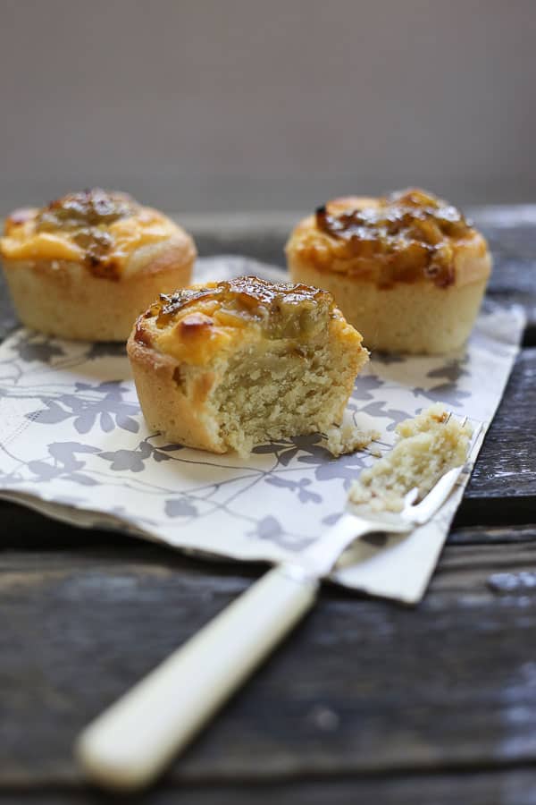 gooseberry friands with a bite taken out on a napkin with a fork on a wooden table