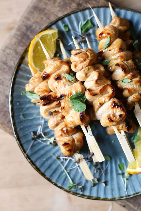 Honey Orange & White Wine Chicken Skewers on a plate with oranges, micro herbs