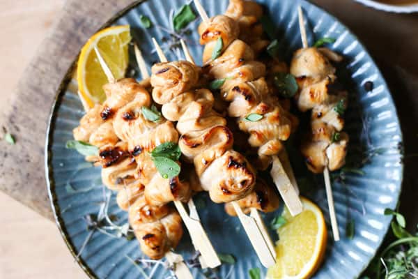 Honey Orange & White Wine Chicken Skewers on a plate with oranges, micro herbs