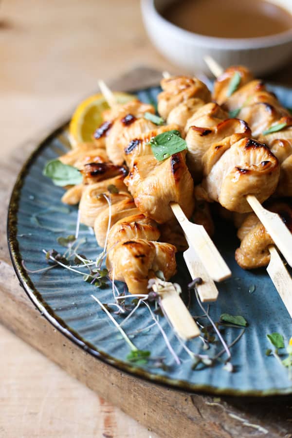 Honey Orange & White Wine Chicken Skewers on a plate with oranges, micro herbs