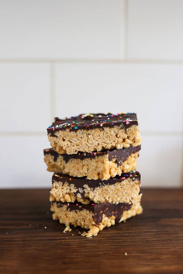 Side view of stacked Chocolate Peanut Butter Crispy Bars on a wooden board