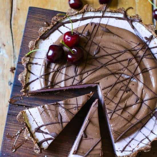 No-Bake Frozen Cherry Chocolate Pie with slices cut on a wooden board on a wooden table with cherries
