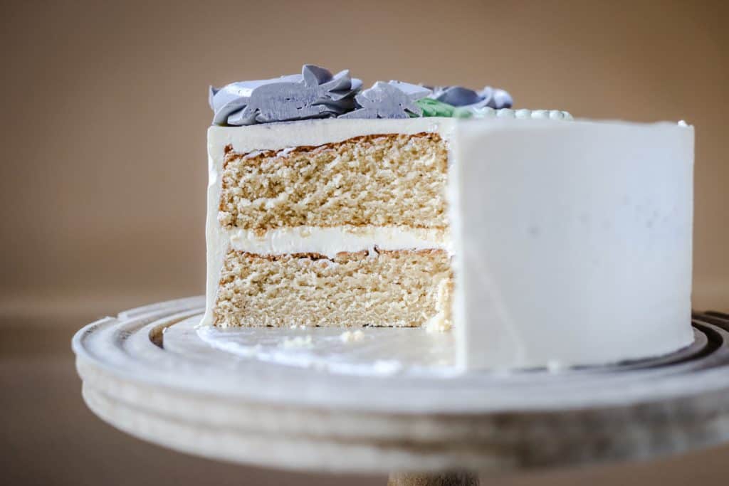 Best Gluten-Free Vanilla Cake on a cake stand on a wooden table