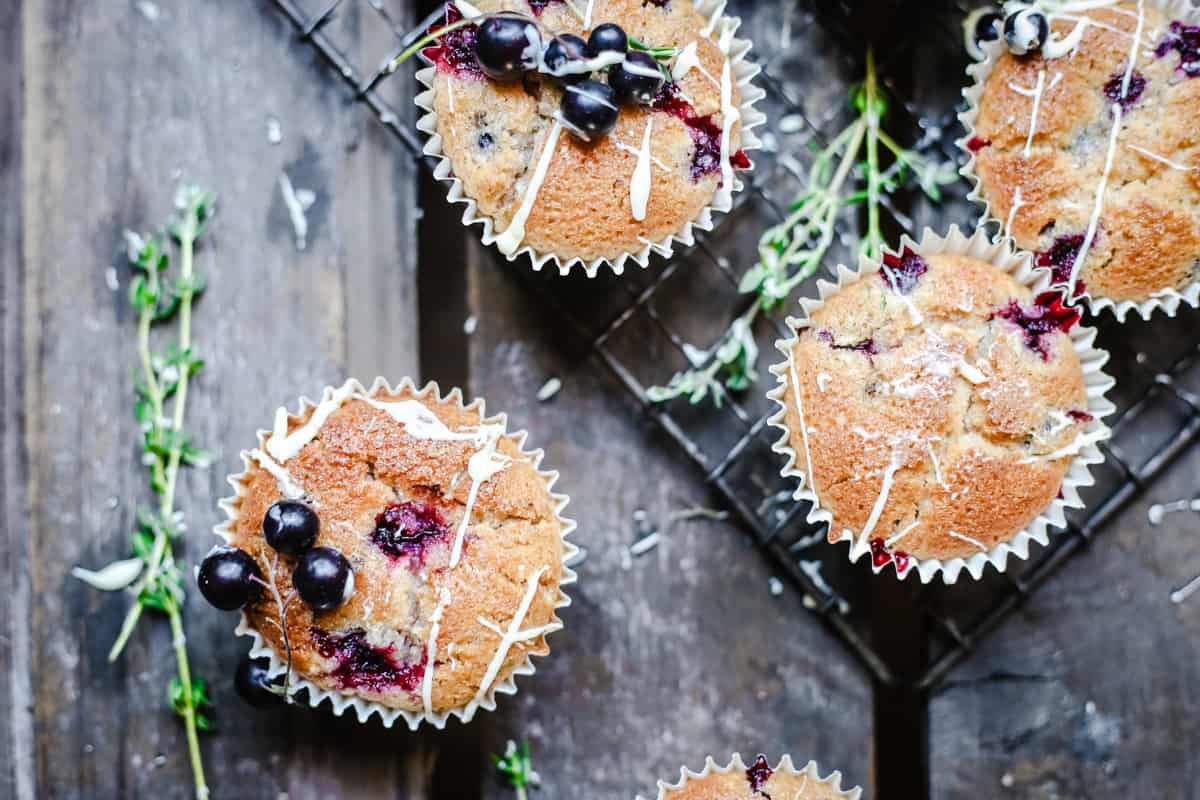 overhead of Blackcurrant White Chocolate and Thyme Muffins on a wooden table