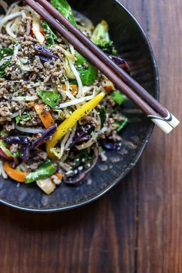 Sriracha Honey Beef Stir Fry in a bowl on a table with chopsticks