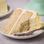 Slice of Gluten-Free Vanilla Layer Cake on a plate with fork ful removed showing creamy buttercream.