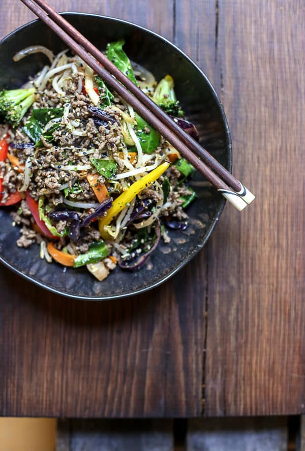 Sriracha Honey Beef Stir Fry in a bowl on a table with chopsticks