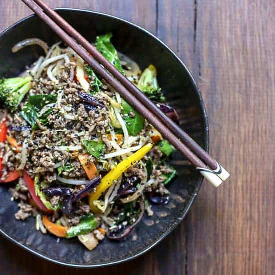 Sriracha Honey Beef Stir Fry in a bowl on a table with chopsticks