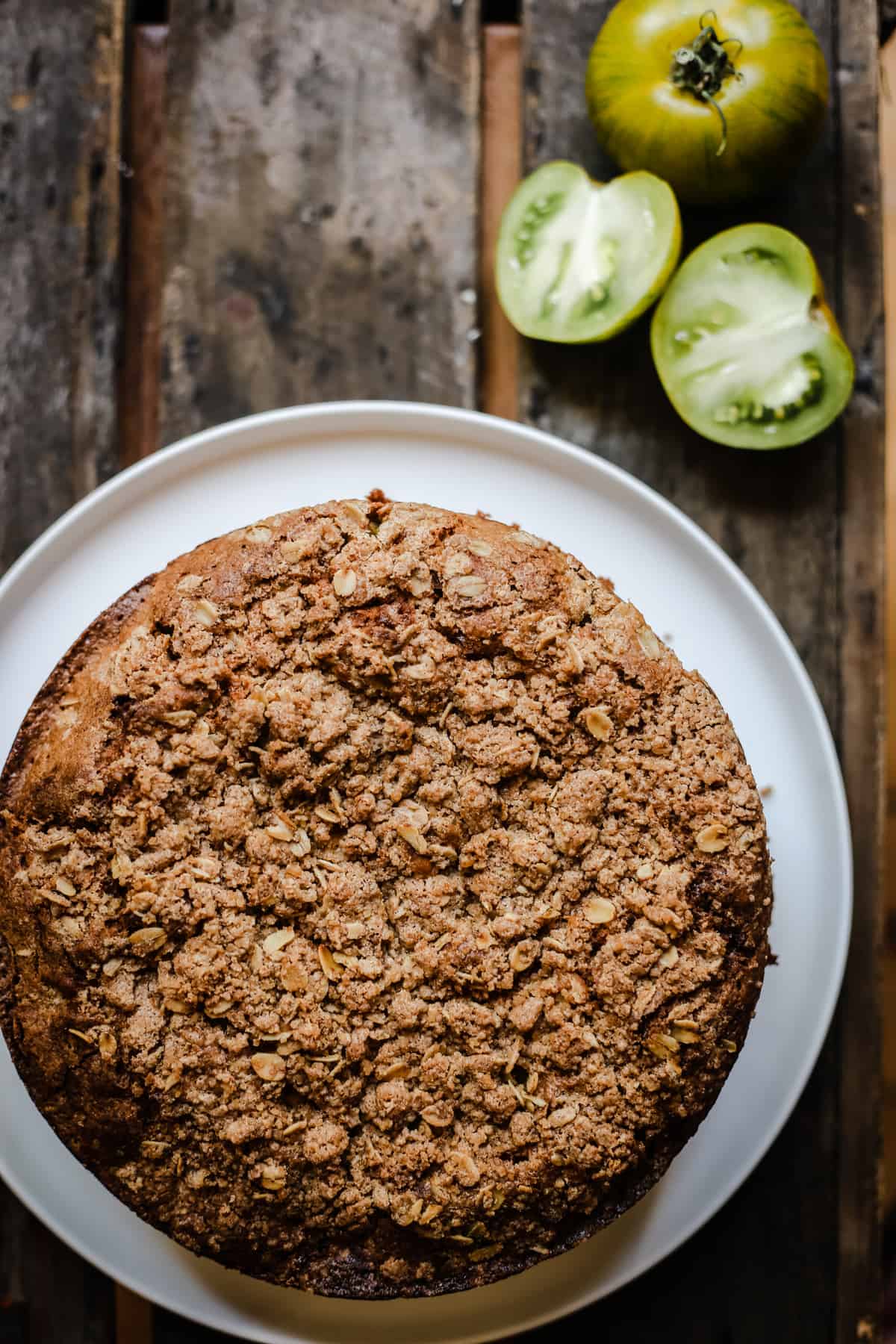 overhead shot of Green Tomato and Stem Ginger Cake with Streusel Topping {gluten-free} on a plate with green tomatoes next to it