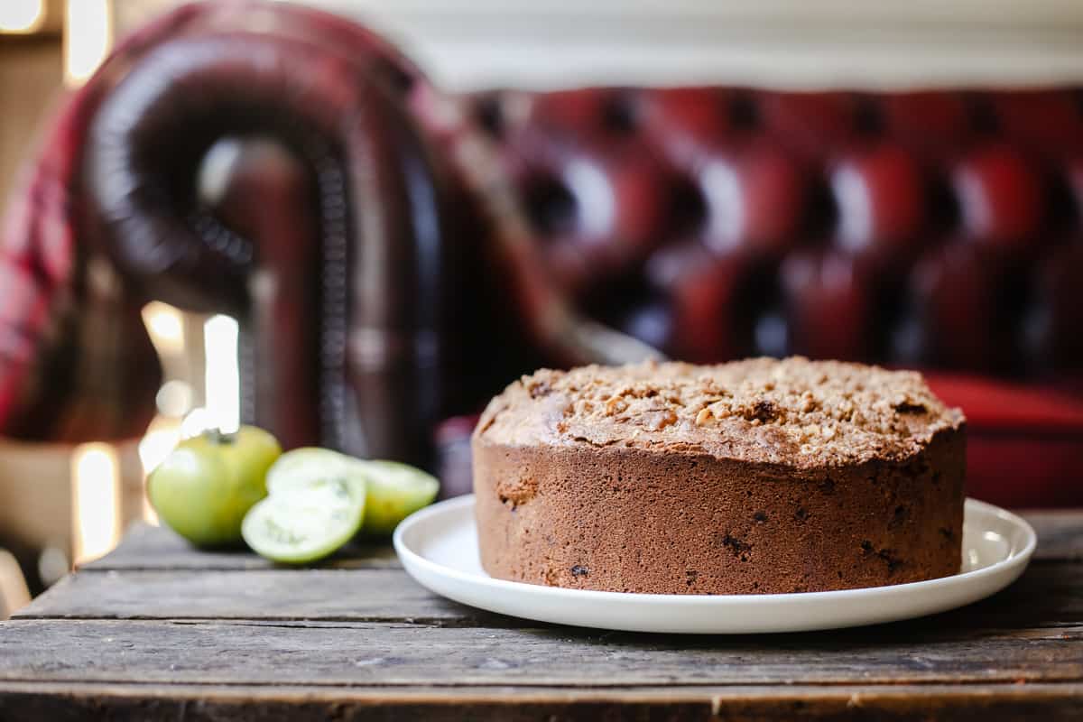 side shot of Green Tomato and Stem Ginger Cake with Streusel Topping {gluten-free} on a plate with green tomatoes next to it