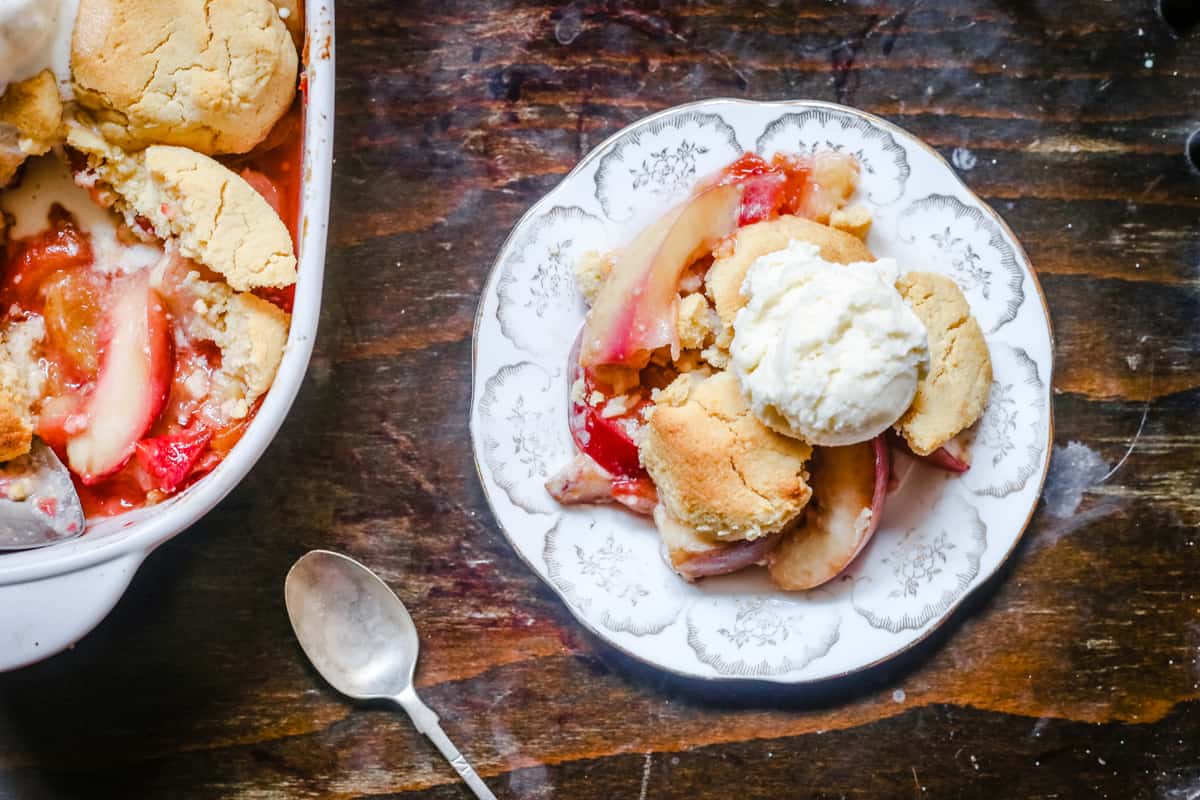 overhead shot of a plate of plum nectarine cornbread cobbler on a table next to a spoon