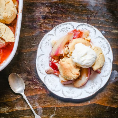overhead shot of a plate of plum nectarine cornbread cobbler on a table next to a spoon