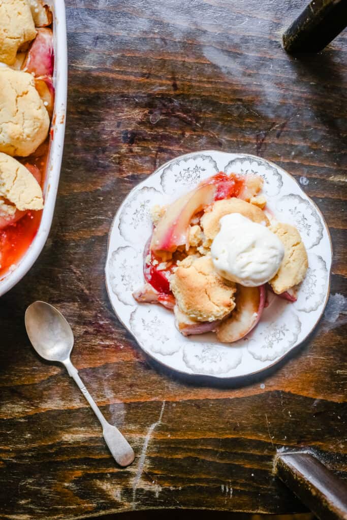 overhead shot of a plate of plum nectarine cornbread cobbler on a table next to a spoon
