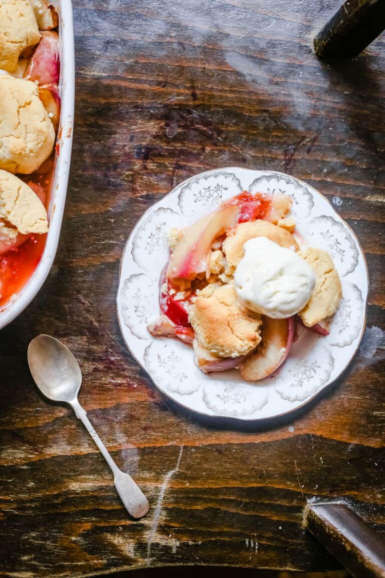overhead shot of a plate of plum nectarine cornbread cobbler on a table next to a spoon