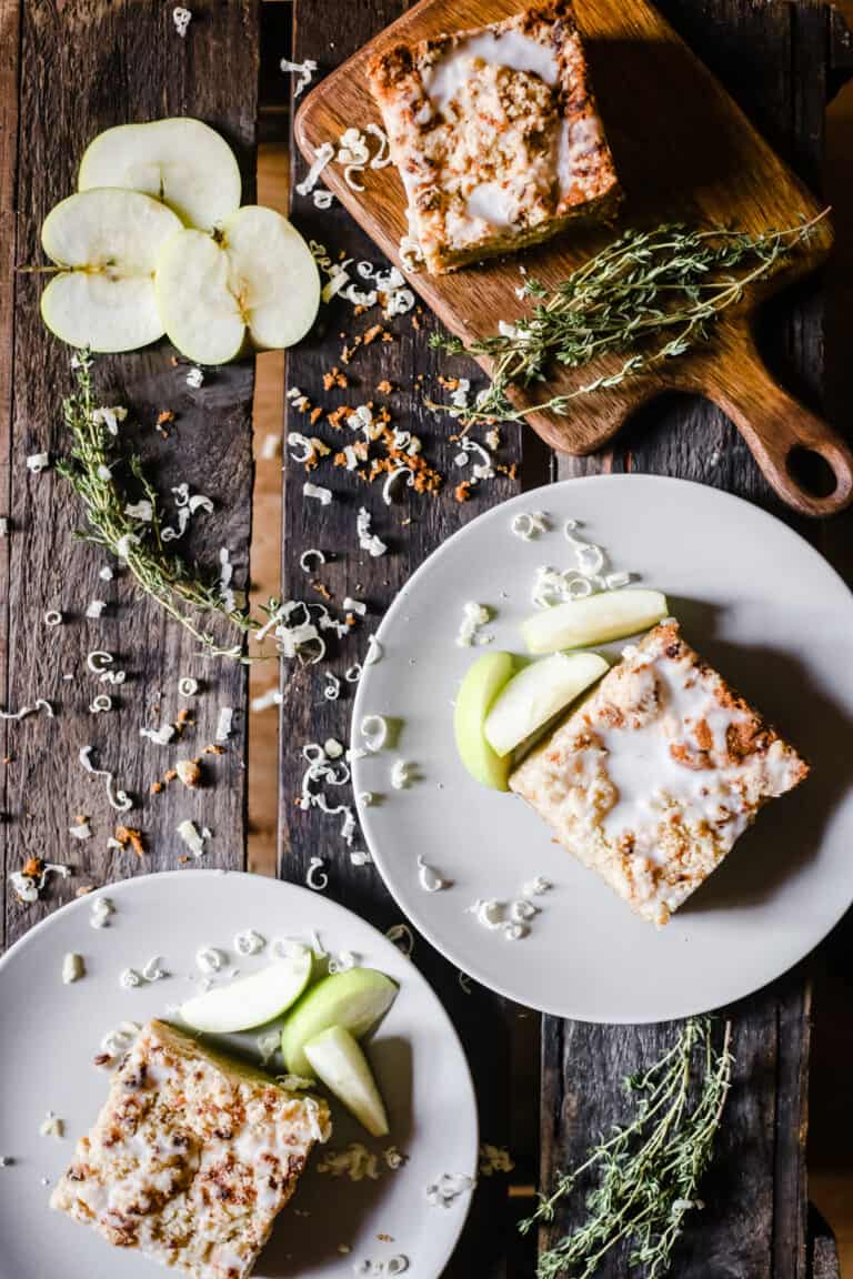 Slices of Apple Cheddar Thyme Crumble Cake on plates on a wooden board