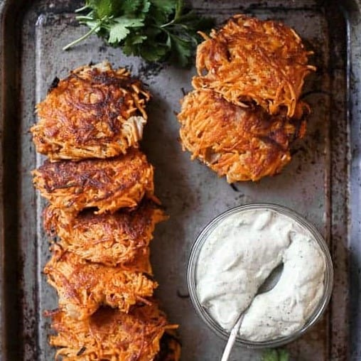 close up of sweet potato rosti on a pan next to sauce