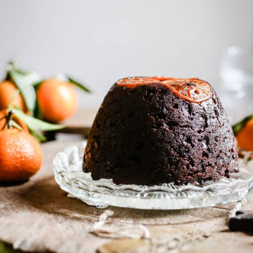 Chocolate Chip Clementine Christmas Pudding on glass plate surrounded by clementines