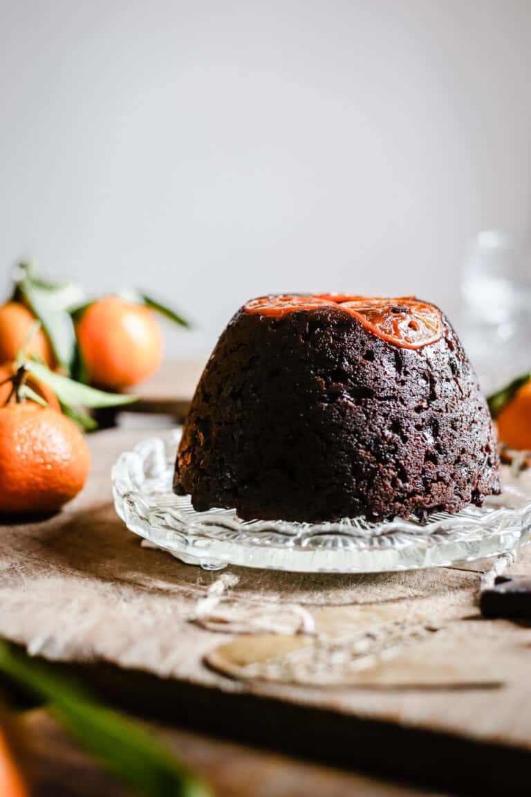 Chocolate Chip Clementine Christmas Pudding on glass plate surrounded by clementines
