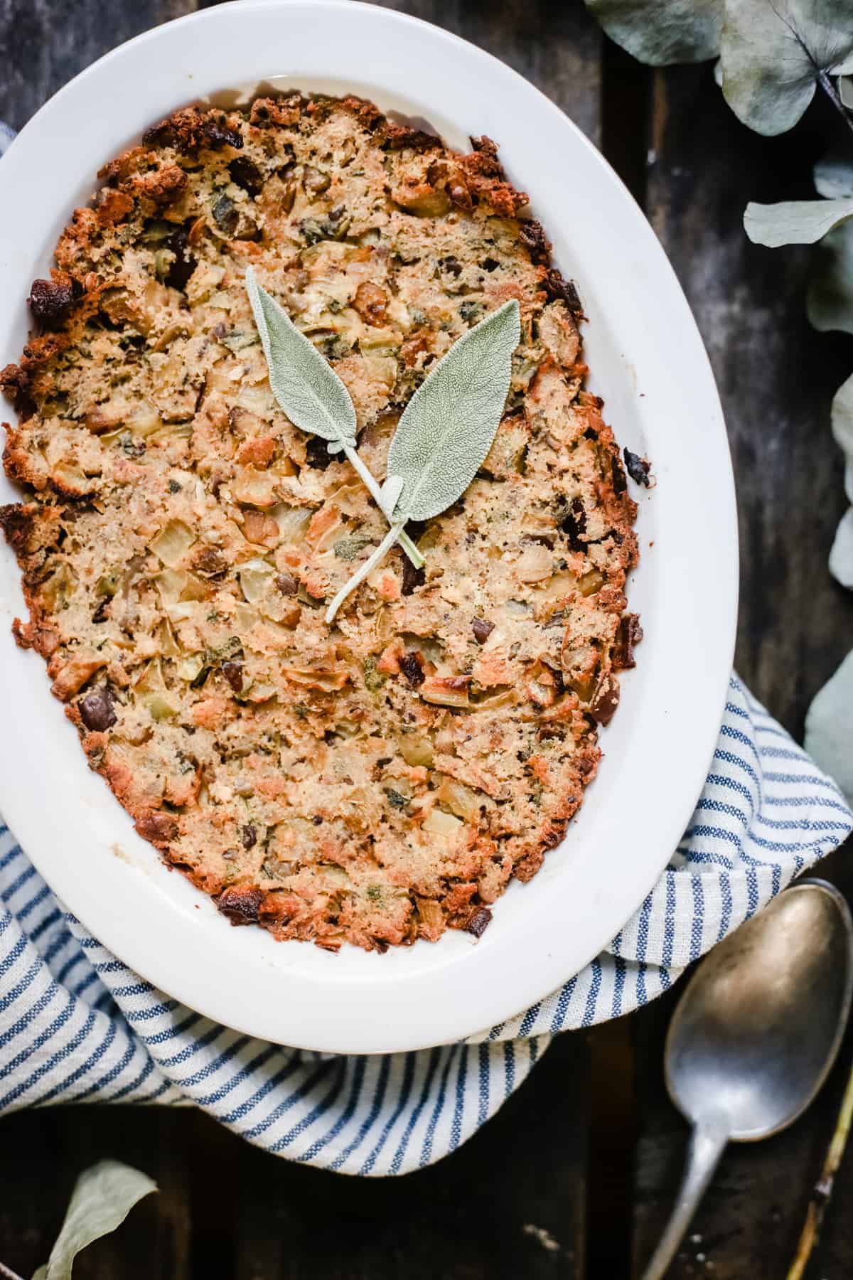 A dish of Chestnut Stuffing on a tea towel surrounded by greenery