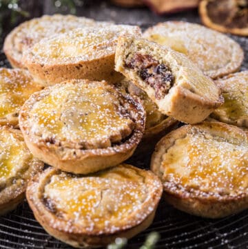 Gluten-Free Mince Pies on a wire rack with bite taken out of one showing the juicy mincemeat filling
