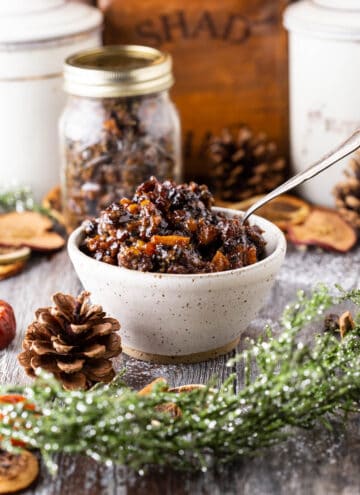 Mincemeat in a bowl with plump fruits glistening, surrounded by Christmas foliage.