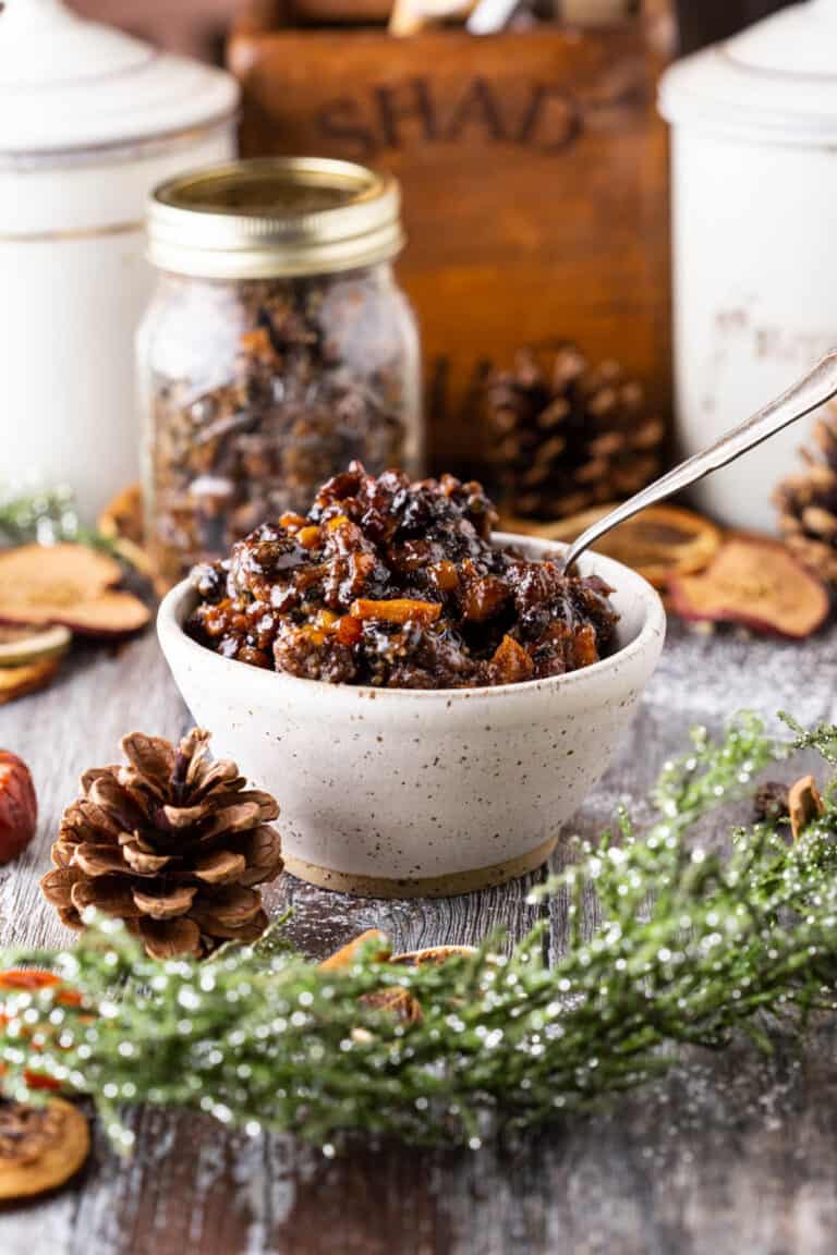 Mincemeat in a bowl with plump fruits glistening, surrounded by Christmas foliage.