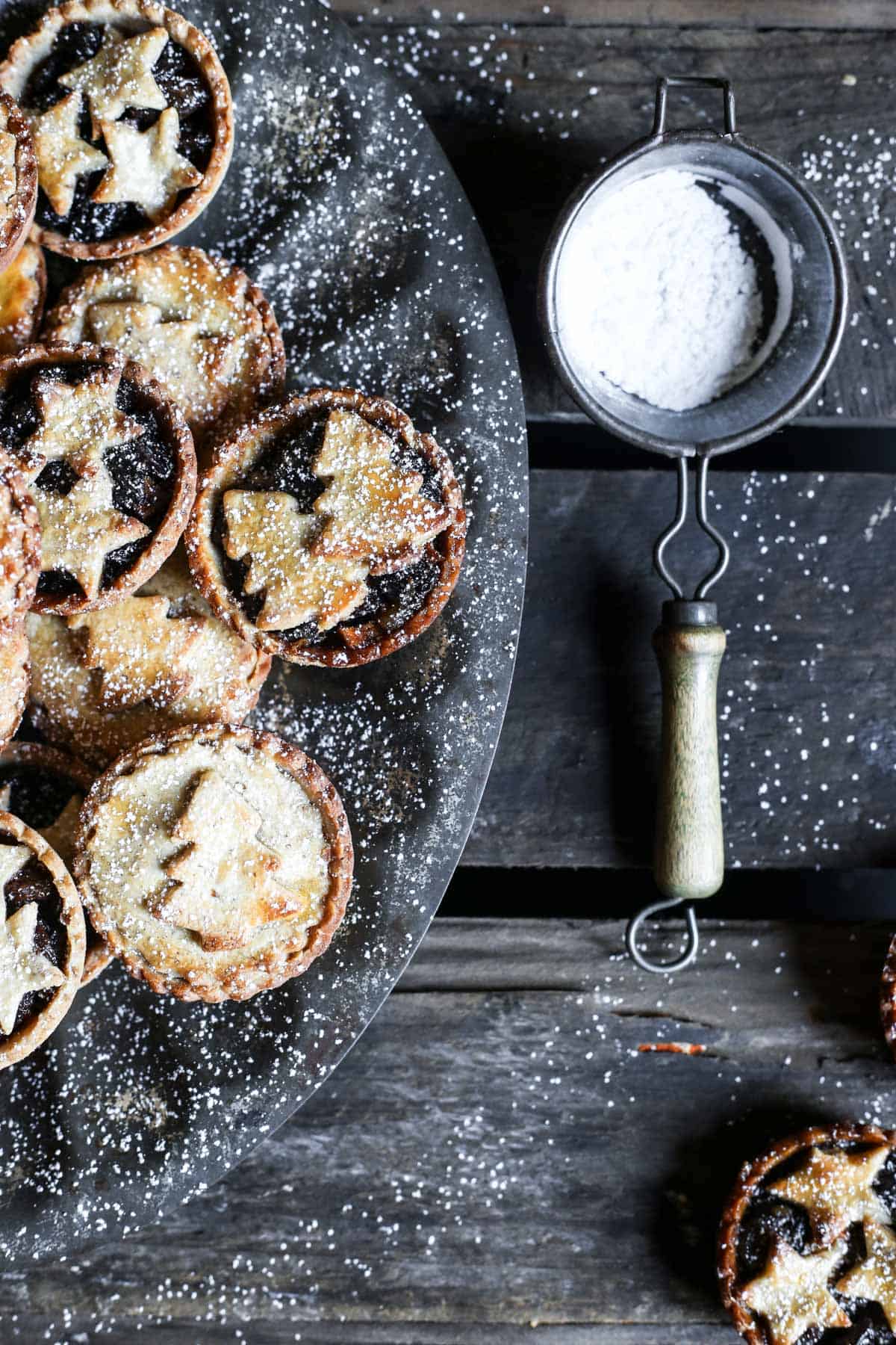 Gluten-Free Mince Pies on a tray next to a sieve with icing sugar