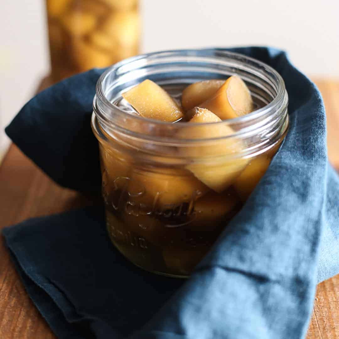 Homemade Stem Ginger in Syrup in a jar with blue linen