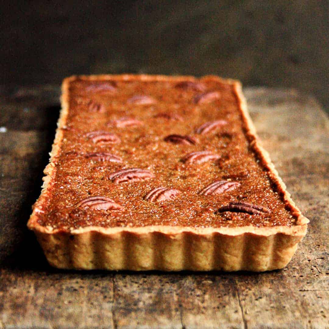 A close up of pecan treacle tart on wooden table