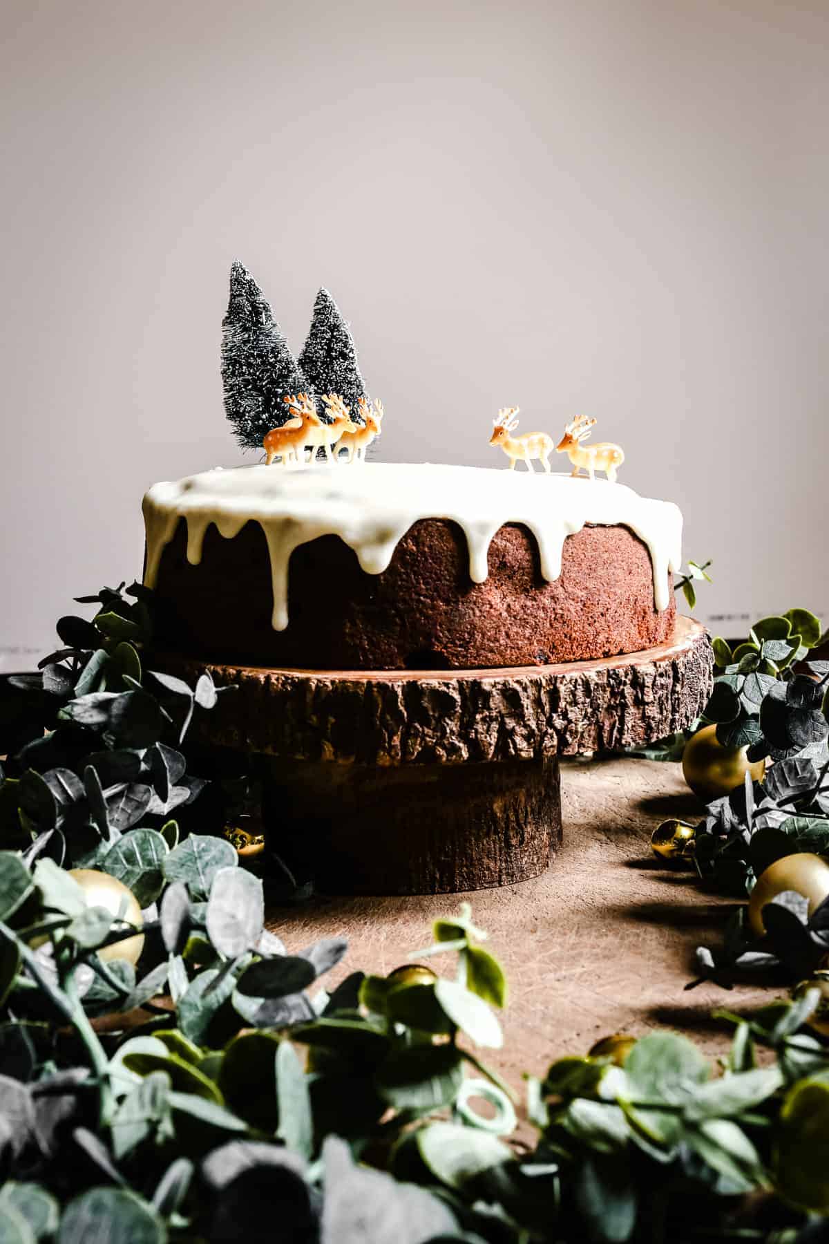 Almond & Mincemeat Christmas Sponge Cake on a cake stand surrounded by greenery