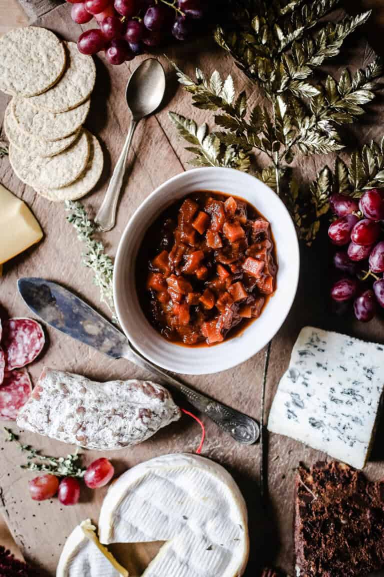 Christmas Ale Chutney in the middle of a cheeseboard, surrounded by salami, cheeses, grapes, Christmas cake and crackers.