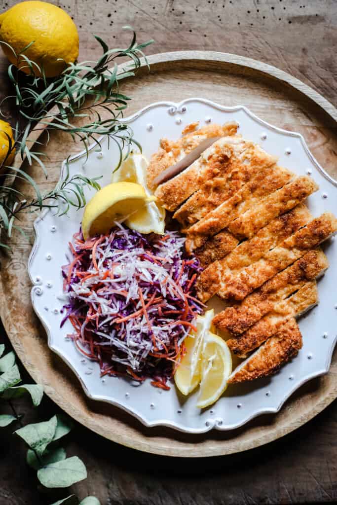 overhead view of Plate of Gluten-Free Chicken Schnitzel with coleslaw and lemon