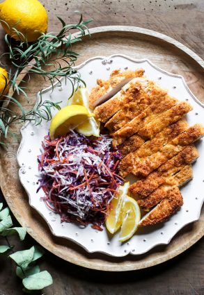 overhead view of Plate of Gluten-Free Chicken Schnitzel with coleslaw and lemon