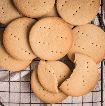 Gluten-free digestive biscuits on a wire rack with one biscuit crisply broken.