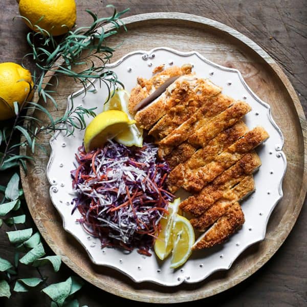 overhead view of Plate of Gluten-Free Chicken Schnitzel with coleslaw and lemon